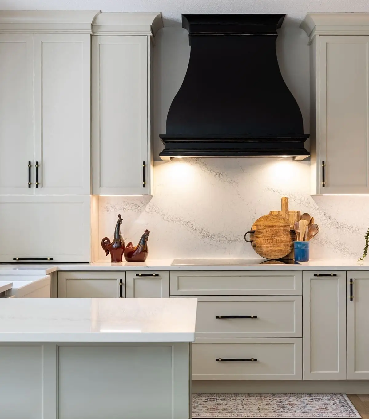 The Italiano Bellissima kitchen: light shaker cabinetry, a black range hood and veined quartz
